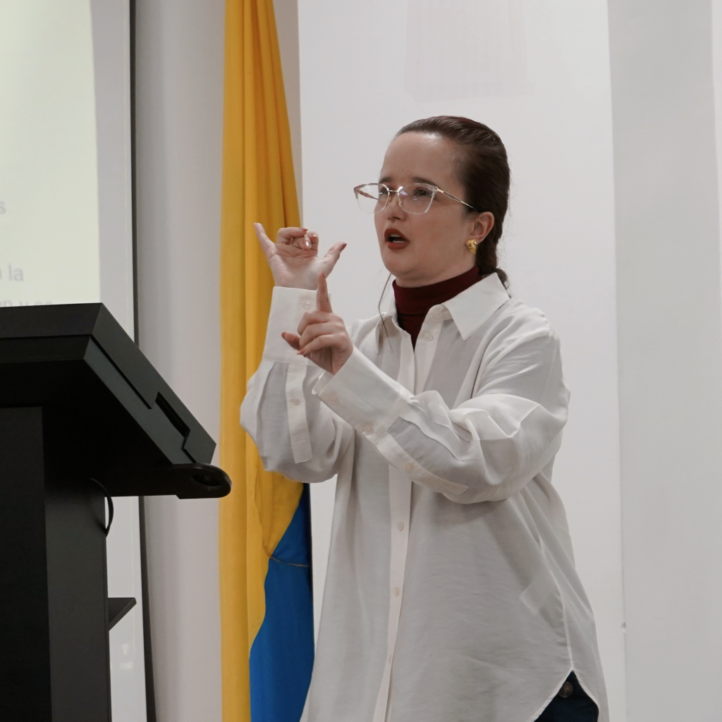 Mujer con camisa blanca y lentes haciendo lengua de señas