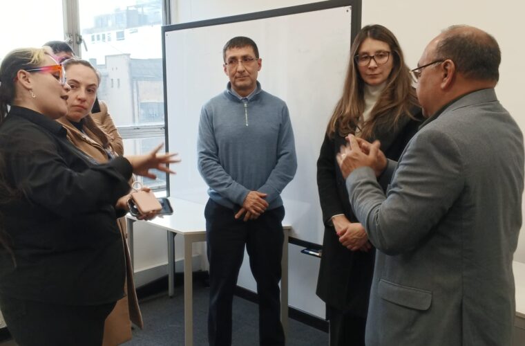 5 personas dialogando en una oficina junto a un tablero